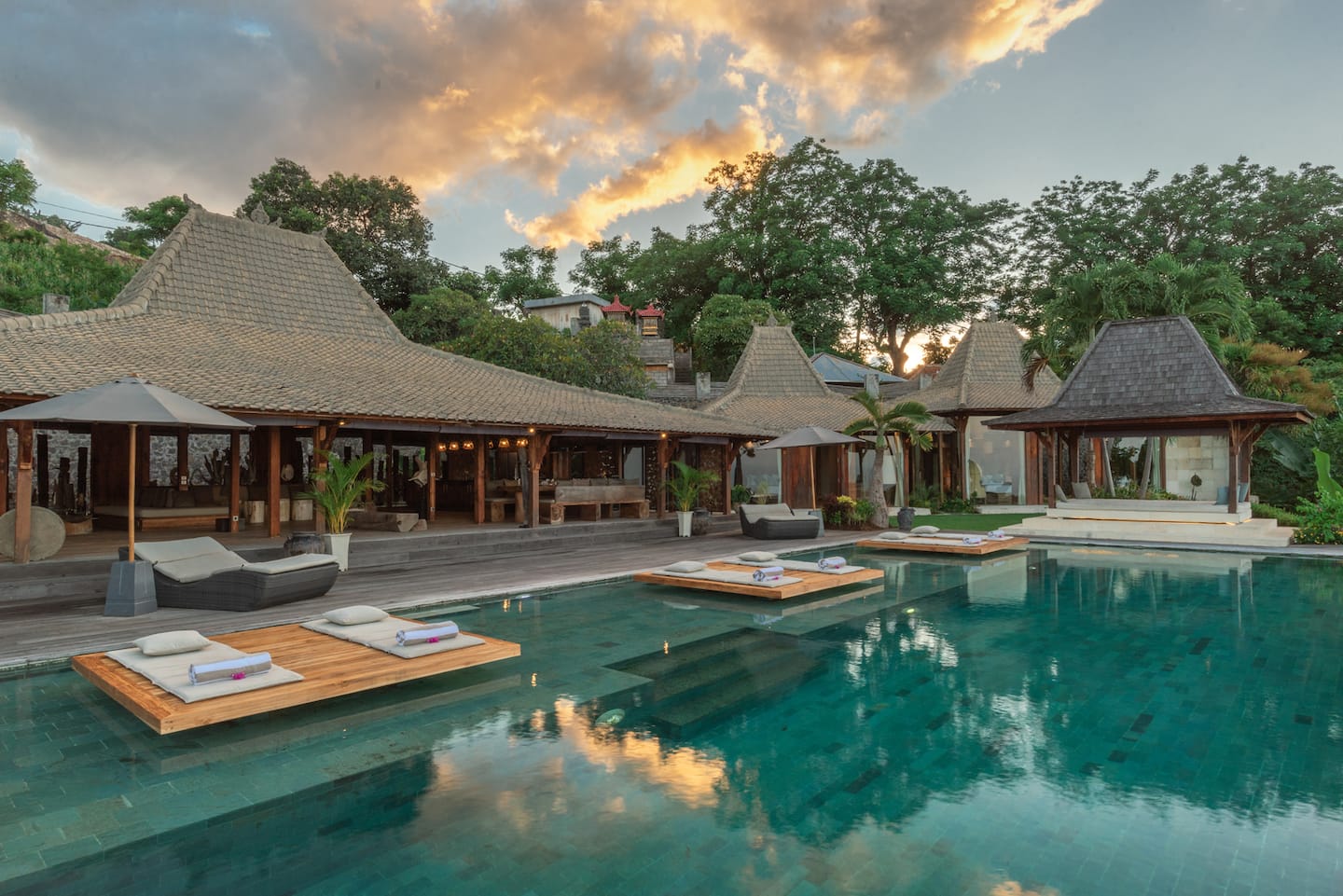 Villa Joglovina’s carved timber pavilions beside the pool at dusk